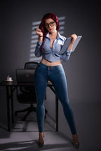 Bubbly 169cm curvy D-cup hybrid sex doll standing by an office desk in an open denim shirt, jeans, heels and glasses