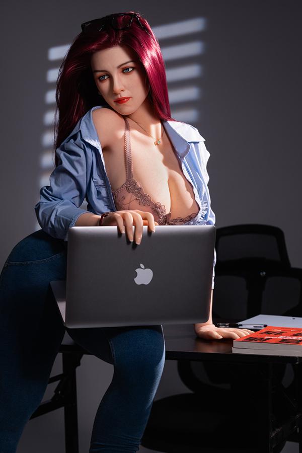 Bubbly curvy hybrid sex doll at an office desk with a laptop, in a lace bra and open shirt